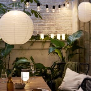 Lauko apšvietimas balkone su LED girliandomis, žibintais ir augalais vasaros vakarui