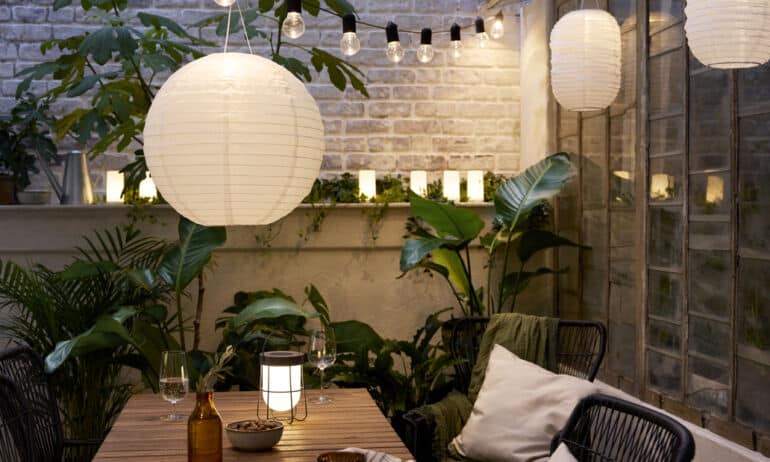 Lauko apšvietimas balkone su LED girliandomis, žibintais ir augalais vasaros vakarui